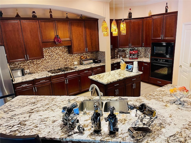 kitchen with a center island, black appliances, hanging light fixtures, tasteful backsplash, and light stone counters