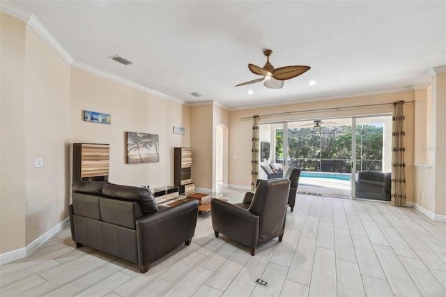 living area featuring arched walkways, ornamental molding, wood finish floors, and visible vents