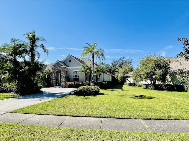 view of front of house with a front yard, stone siding, driveway, and stucco siding