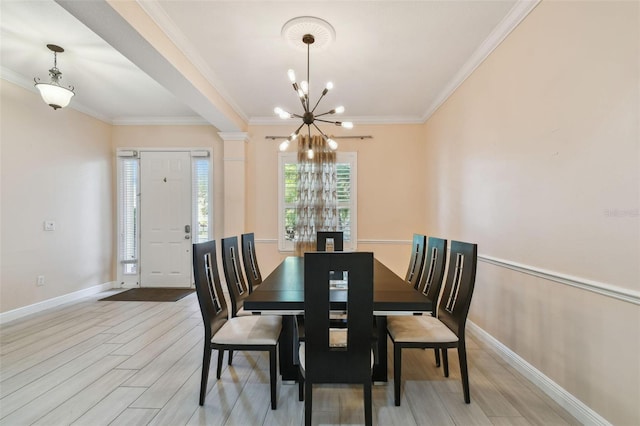 dining room with crown molding, ornate columns, a chandelier, light wood-type flooring, and baseboards