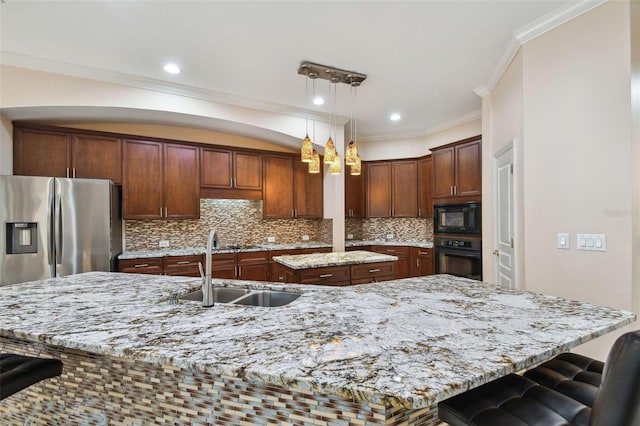 kitchen featuring a sink, black appliances, an island with sink, and light stone countertops