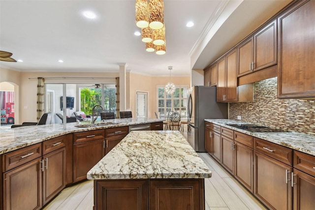 kitchen featuring hanging light fixtures, light stone counters, a kitchen island, and a sink