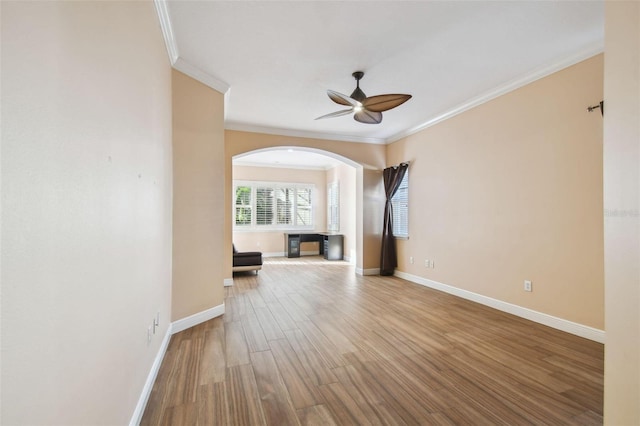 unfurnished living room with a ceiling fan, crown molding, baseboards, and wood finished floors