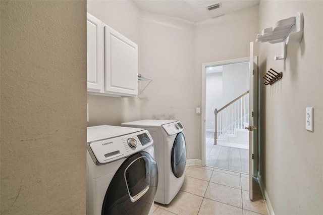 clothes washing area featuring cabinet space, light tile patterned floors, visible vents, baseboards, and washing machine and dryer