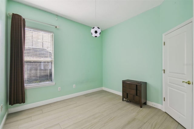 empty room with baseboards and light wood-style floors