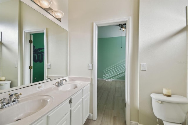 bathroom featuring double vanity, wood finished floors, a sink, and toilet