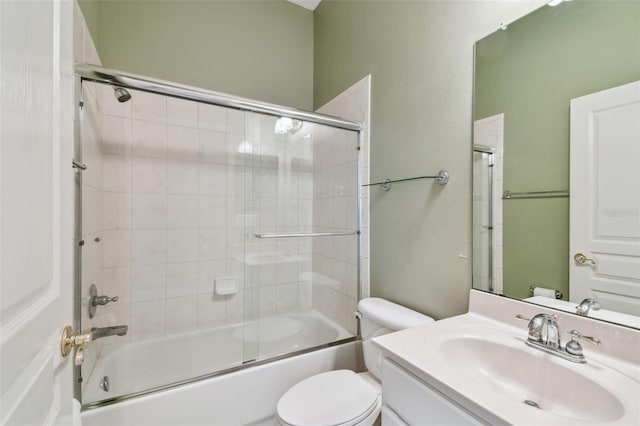 bathroom featuring toilet, combined bath / shower with glass door, and vanity