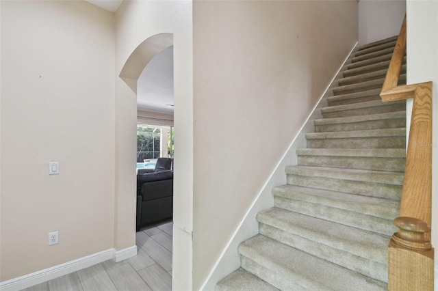 stairs with arched walkways and baseboards