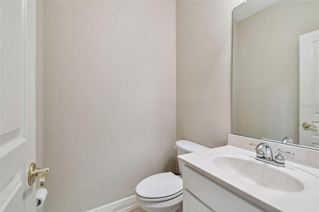 half bath featuring toilet, baseboards, and vanity