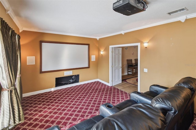 home theater with baseboards, carpet flooring, visible vents, and crown molding