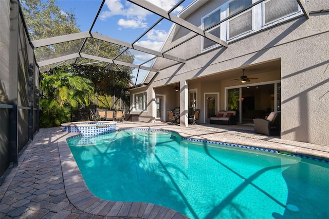 view of pool with a patio, a pool with connected hot tub, a ceiling fan, a lanai, and an outdoor living space