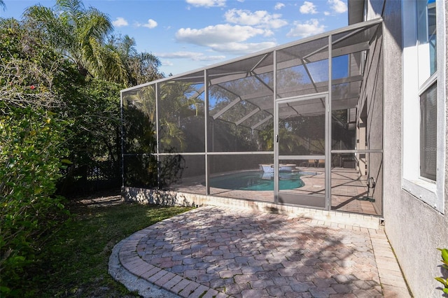 outdoor pool featuring glass enclosure and a patio