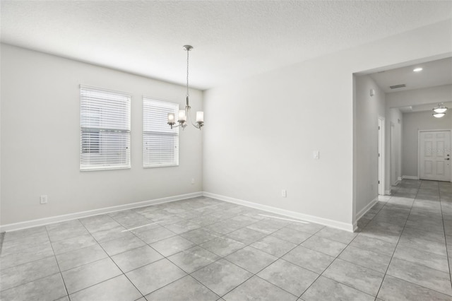 empty room featuring light tile patterned floors, a chandelier, and a textured ceiling