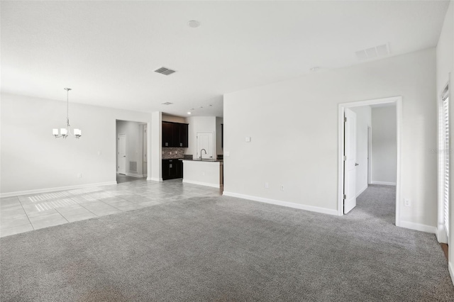 unfurnished living room with sink, light carpet, and a chandelier