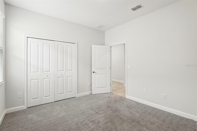 unfurnished bedroom with light carpet and a closet