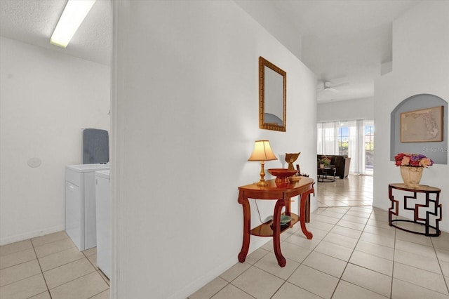 hall with light tile patterned flooring, independent washer and dryer, and a textured ceiling