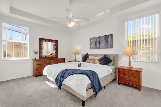 carpeted bedroom featuring ceiling fan and a tray ceiling