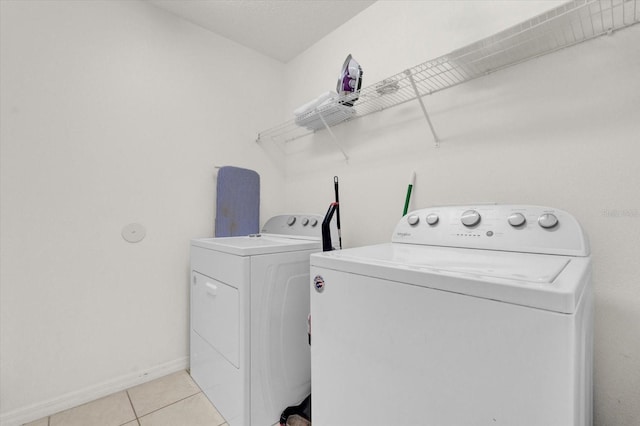 laundry area with washing machine and dryer and light tile patterned floors