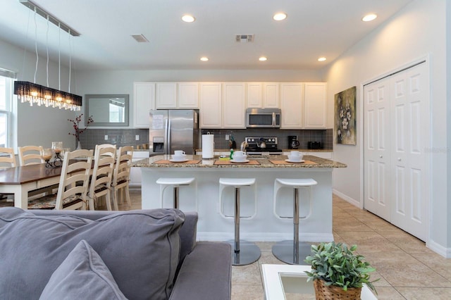 kitchen featuring decorative backsplash, stainless steel appliances, a kitchen island, and pendant lighting