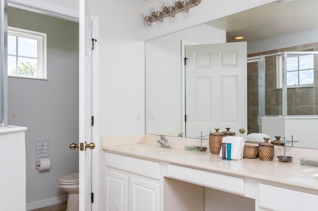 bathroom featuring a shower with door, vanity, and toilet