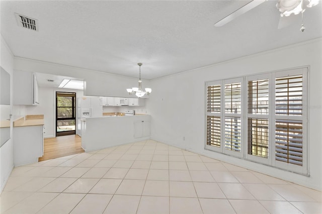 unfurnished dining area with crown molding, a textured ceiling, light tile patterned flooring, and ceiling fan with notable chandelier