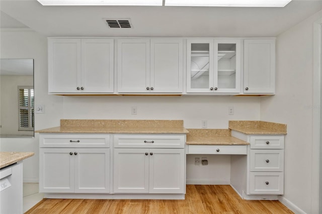 kitchen featuring light stone counters, white dishwasher, light wood-type flooring, and white cabinets