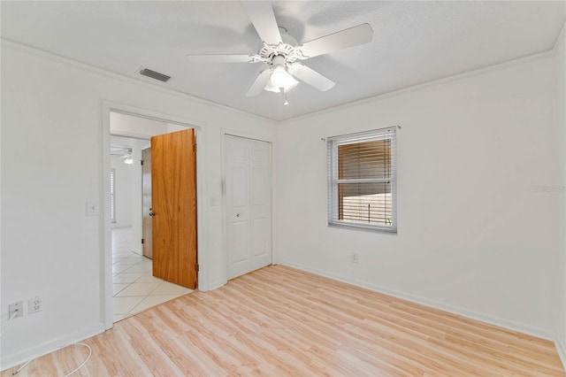 unfurnished bedroom featuring light hardwood / wood-style flooring, ornamental molding, a closet, and ceiling fan