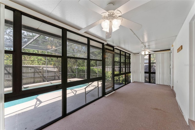 unfurnished sunroom featuring ceiling fan, a wealth of natural light, and a pool