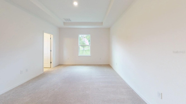 carpeted empty room with a tray ceiling