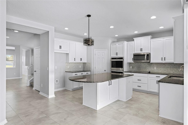 kitchen featuring a center island, dark stone countertops, stainless steel appliances, and backsplash