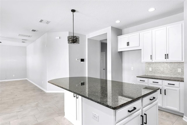 kitchen featuring white cabinetry, a center island, dark stone counters, and decorative light fixtures