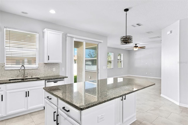 kitchen with dark stone countertops, a center island, sink, and plenty of natural light