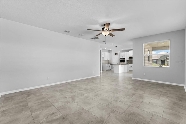 unfurnished living room featuring a textured ceiling, light tile patterned floors, and ceiling fan