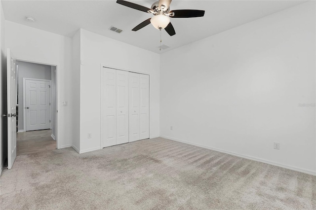 unfurnished bedroom featuring a closet, light colored carpet, and ceiling fan