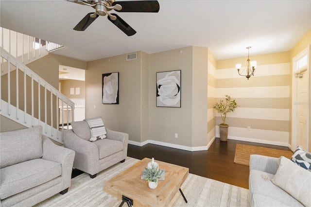 living room with ceiling fan with notable chandelier and dark hardwood / wood-style flooring