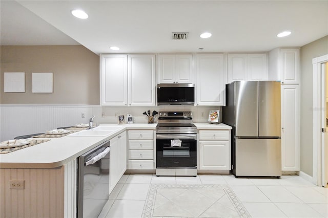 kitchen with kitchen peninsula, light tile patterned floors, appliances with stainless steel finishes, white cabinetry, and sink