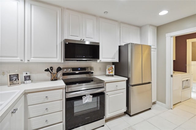 kitchen featuring washer and dryer, light tile patterned flooring, backsplash, stainless steel appliances, and white cabinets