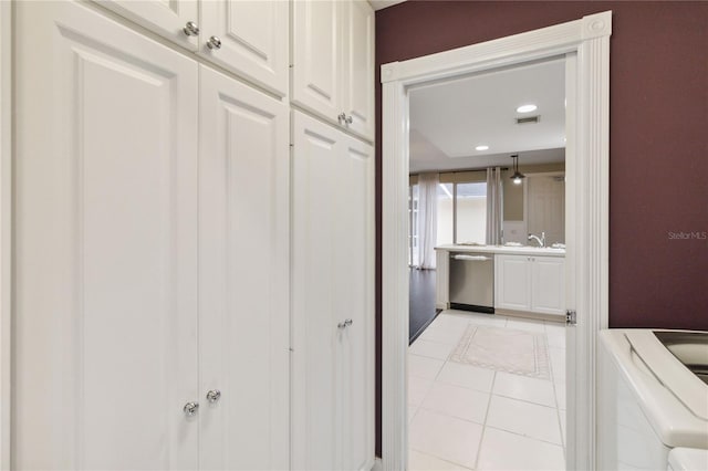 hallway with washer / dryer, sink, and light tile patterned floors