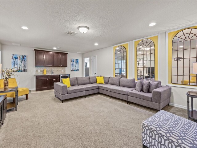 8832 Macapa Dr, Kissimmee, FL 34747 - living area featuring light carpet, bar with sink, recessed lighting, baseboards, and a textured ceiling