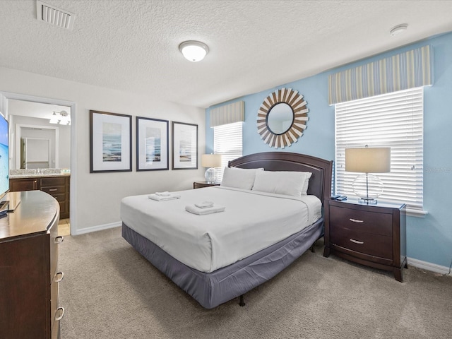 bedroom featuring connected bathroom, light carpet, and a textured ceiling