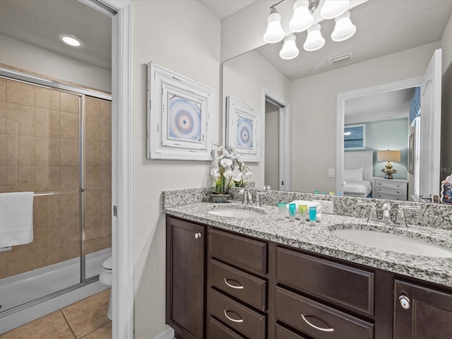 bathroom with a textured ceiling, toilet, vanity, an enclosed shower, and tile patterned floors