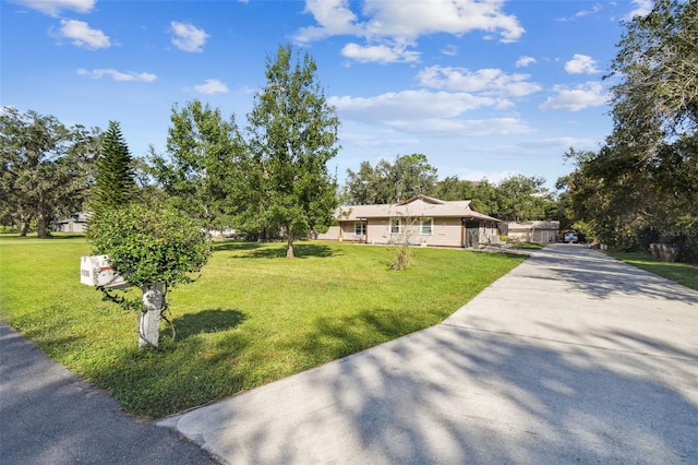 ranch-style house featuring concrete driveway and a front lawn