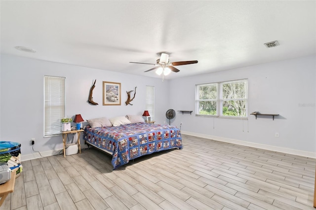 bedroom featuring visible vents, ceiling fan, baseboards, and wood finished floors