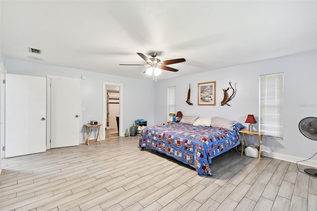 bedroom featuring ceiling fan, visible vents, baseboards, and light wood-style flooring