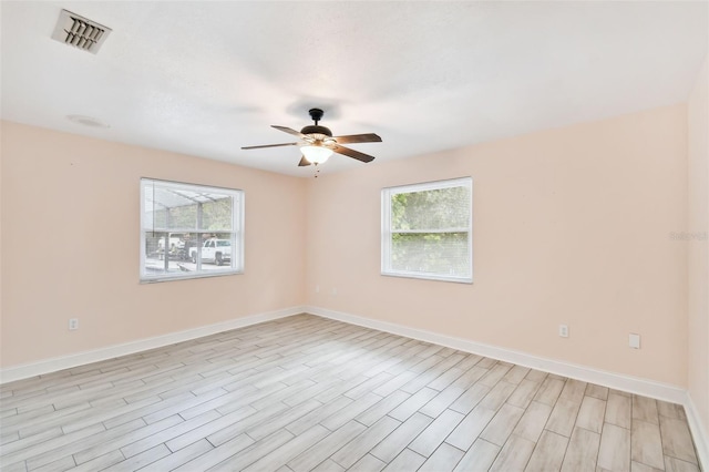 unfurnished room featuring visible vents, plenty of natural light, a ceiling fan, and baseboards