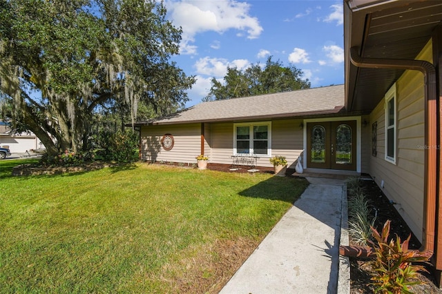 view of front of home featuring french doors, a front yard, and roof with shingles