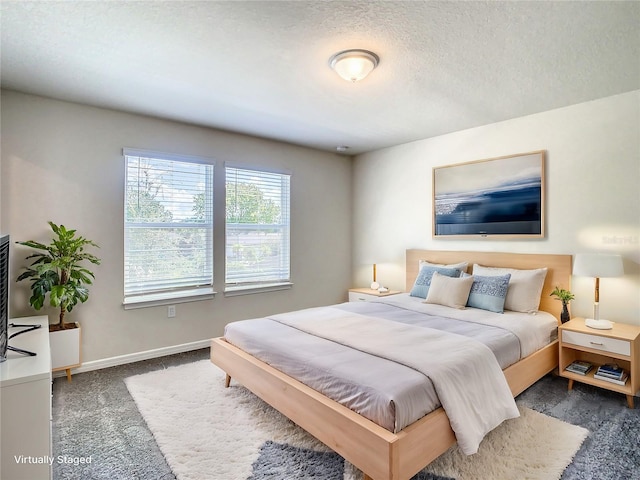 bedroom with dark colored carpet and a textured ceiling