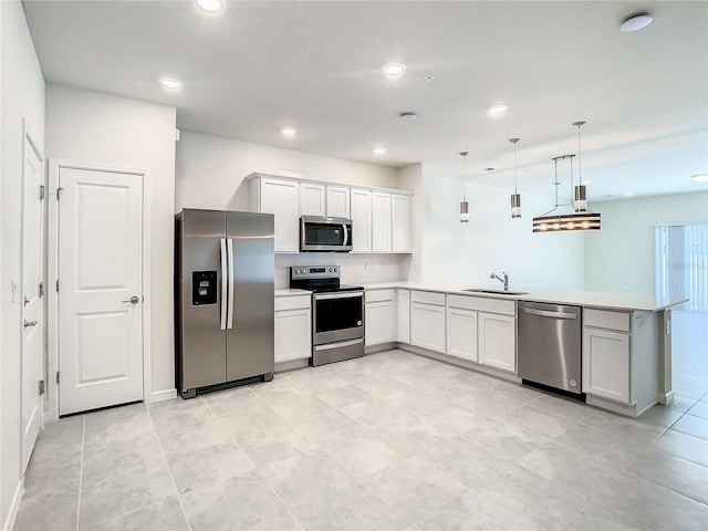 kitchen with kitchen peninsula, appliances with stainless steel finishes, white cabinetry, sink, and decorative light fixtures