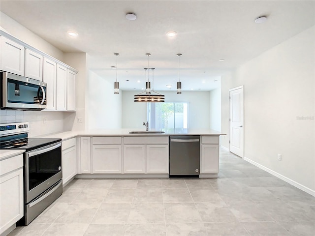 kitchen with appliances with stainless steel finishes, sink, kitchen peninsula, hanging light fixtures, and white cabinetry