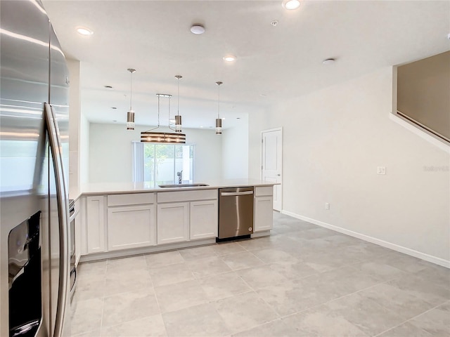 kitchen featuring appliances with stainless steel finishes, white cabinetry, sink, and hanging light fixtures